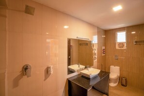 A modern bathroom with two sinks, a mirror, a toilet, and a trash bin. - goSTOPS Ooty (Ooty)