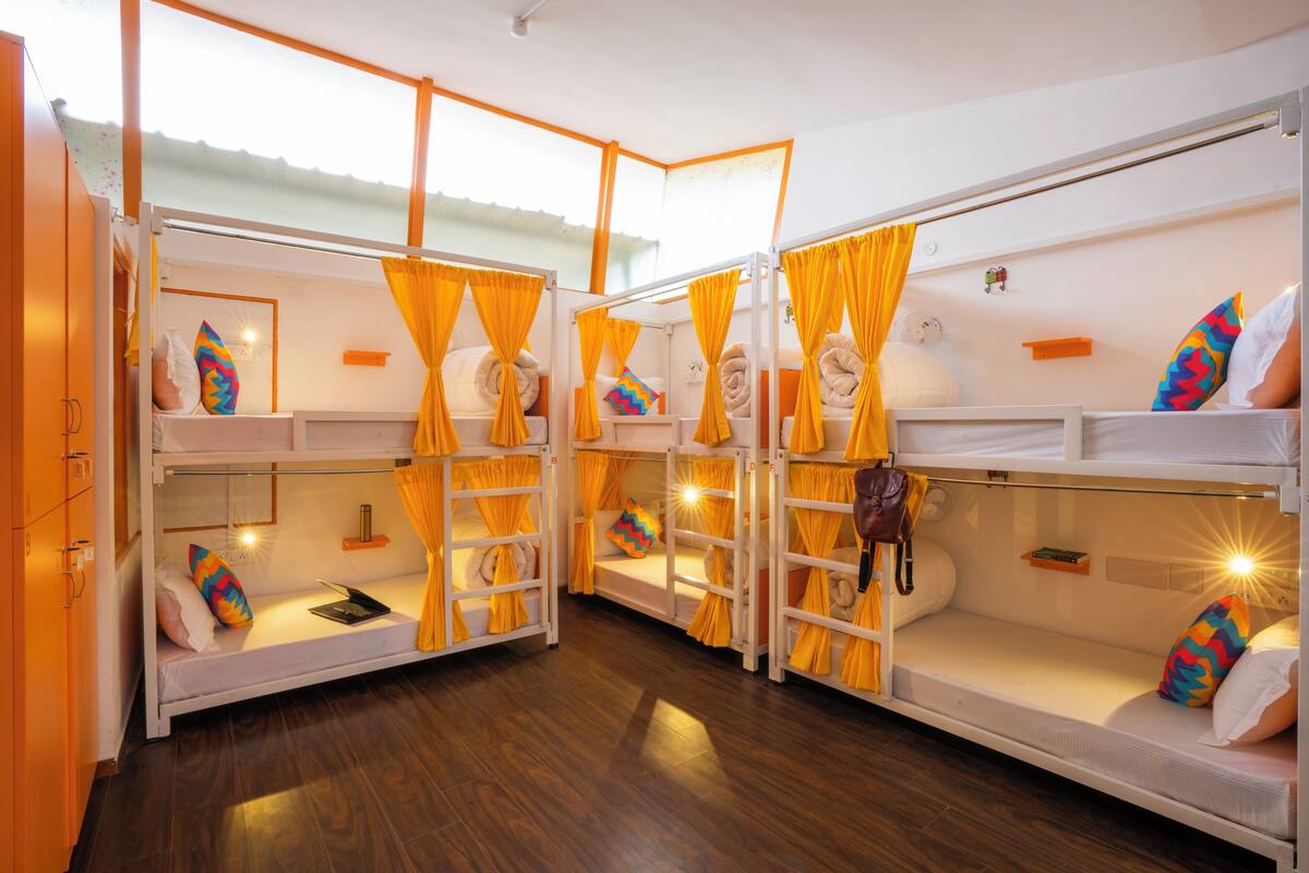 A room with bunk beds, each with a pillow and a small table.