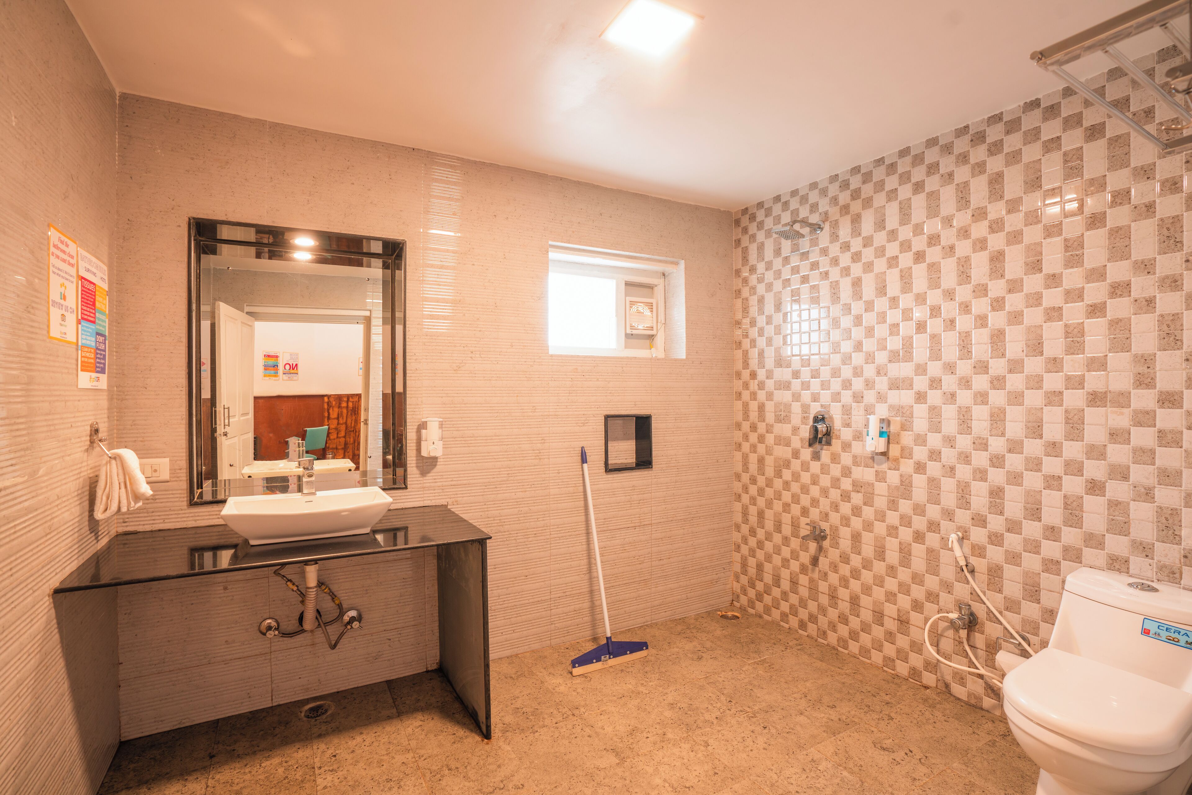 A bathroom with a sink, mirror, toilet, and a broom.