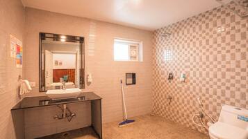 A bathroom with a sink, mirror, toilet, and a broom.