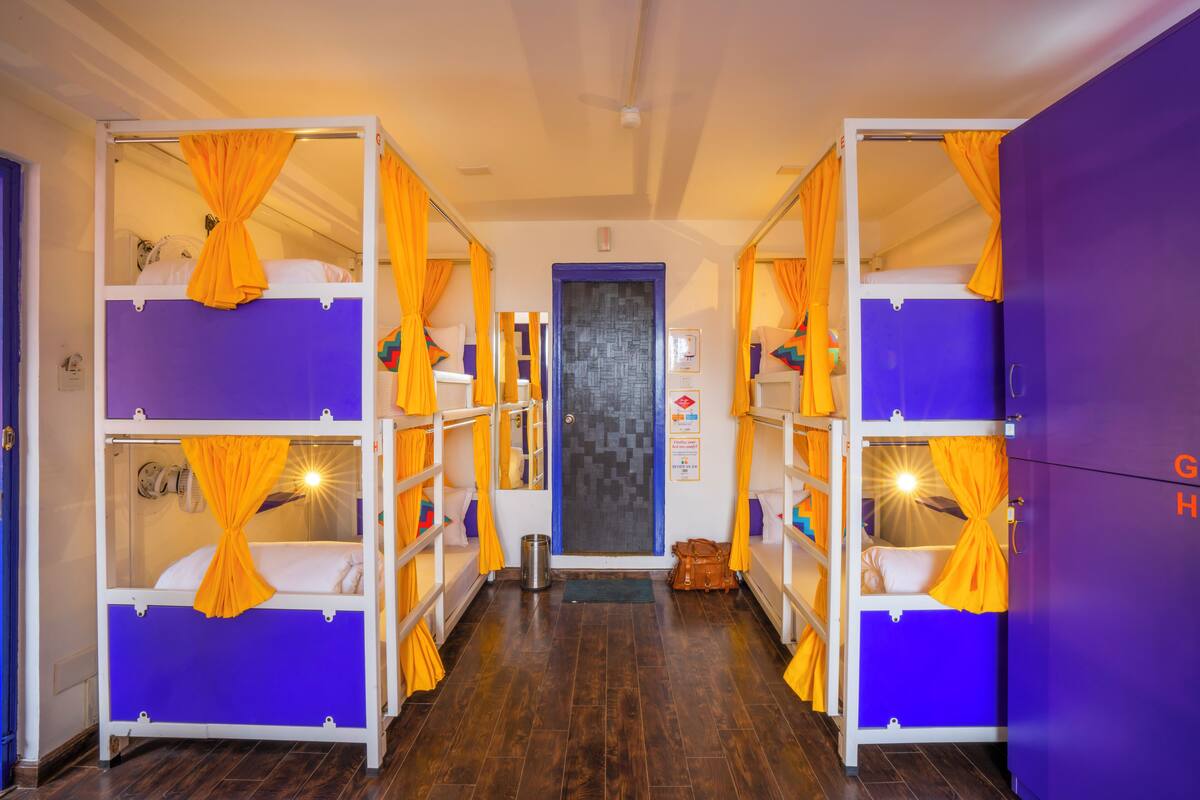 A room with bunk beds, each with orange curtains, and a door with a geometric pattern.