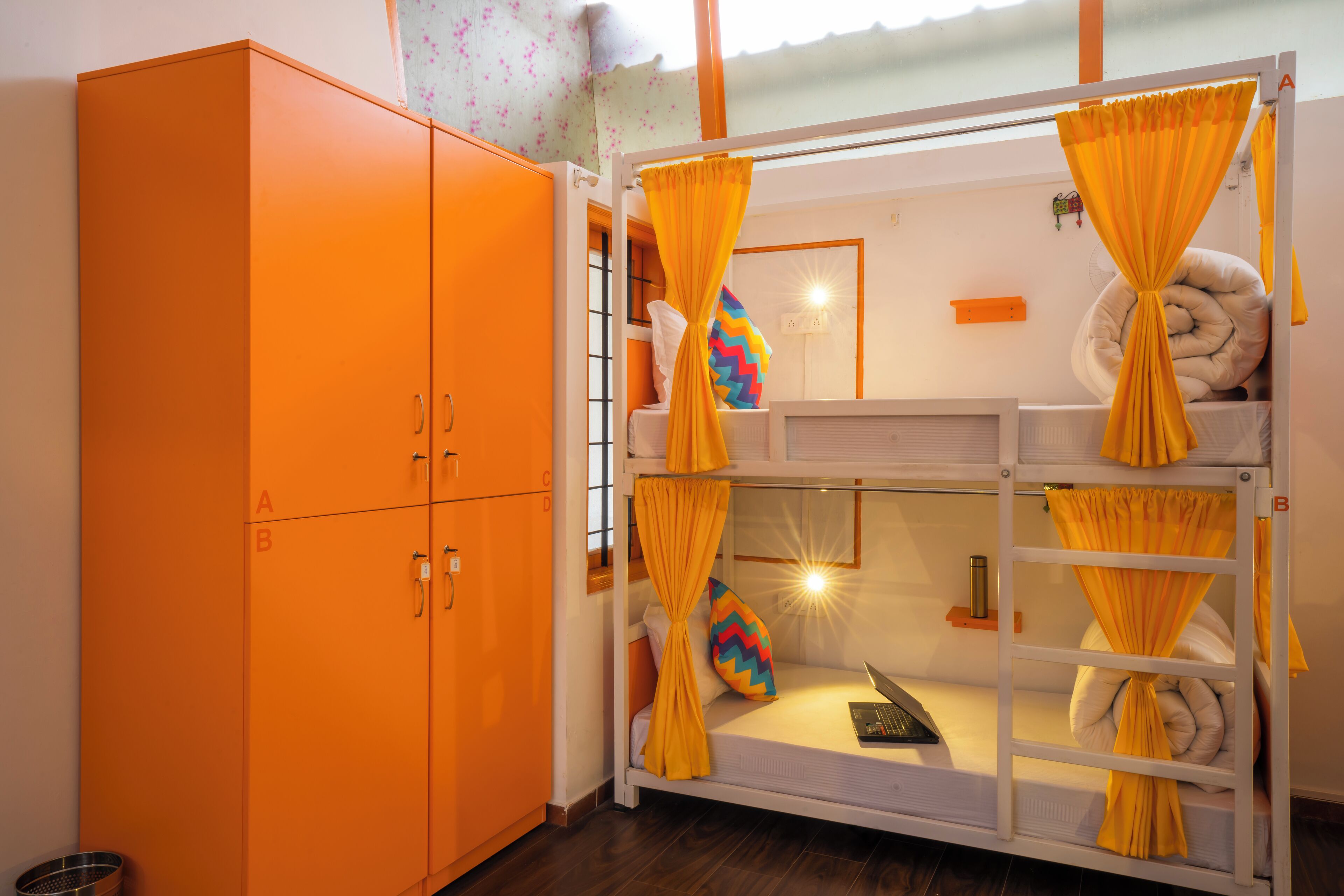 A bunk bed with yellow curtains, a white headboard, and a colorful pillow.