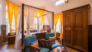 A room with a four-poster bed, a wooden wardrobe, and a dining table with chairs.