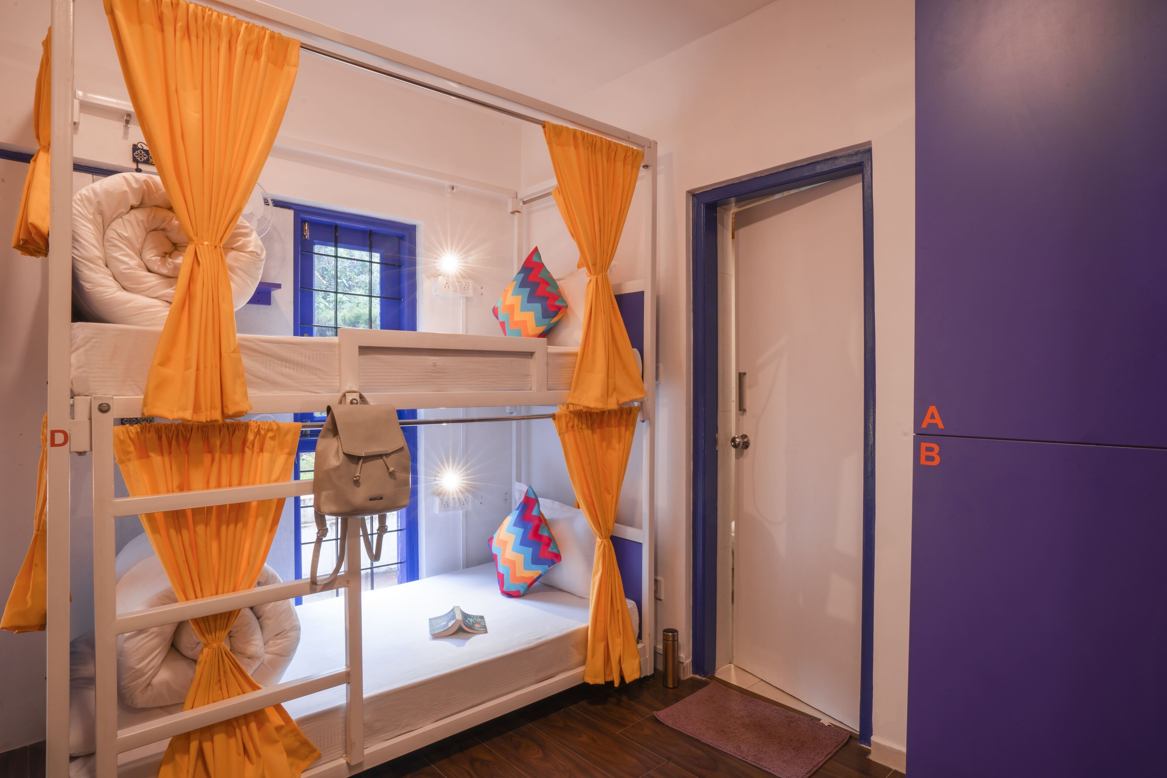 A bunk bed room with orange curtains, a blue door, and a purple wall.