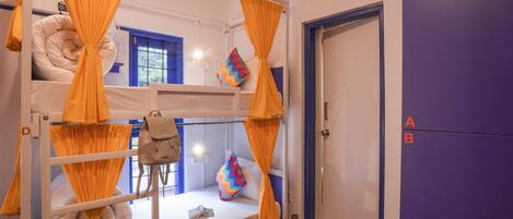 A bunk bed room with orange curtains, a blue door, and a purple wall.