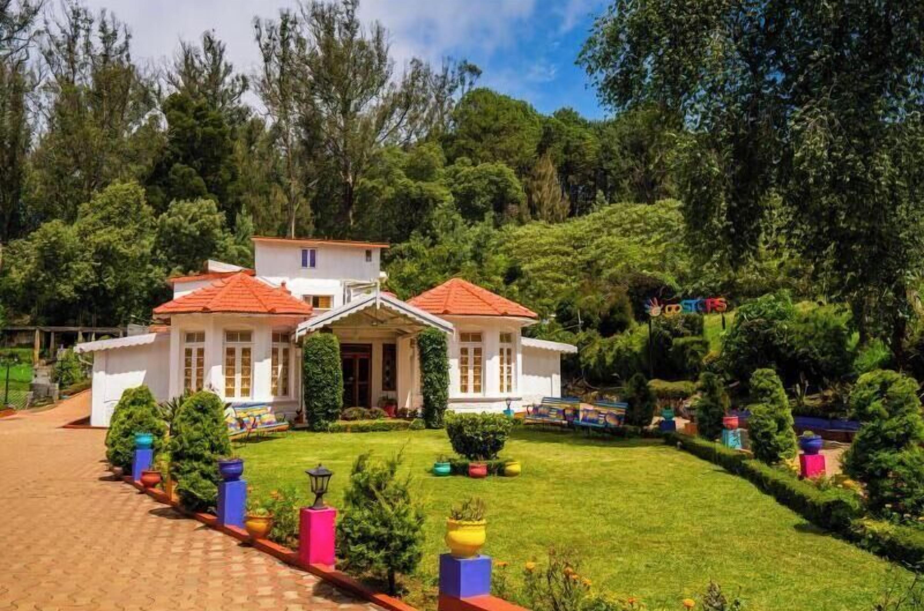 A two-story house with a red roof, surrounded by lush greenery and a well-maintained lawn.