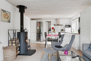 A modern living room with a fireplace, a dining area, and a kitchen.