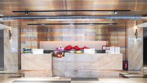 Ein Empfangsbereich mit einer Marmor-Rezeption, einer dekorativen roten Skulptur und einer Blumenkomposition.