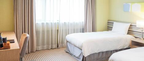 Habitación de hotel con dos camas, un escritorio y una silla.
