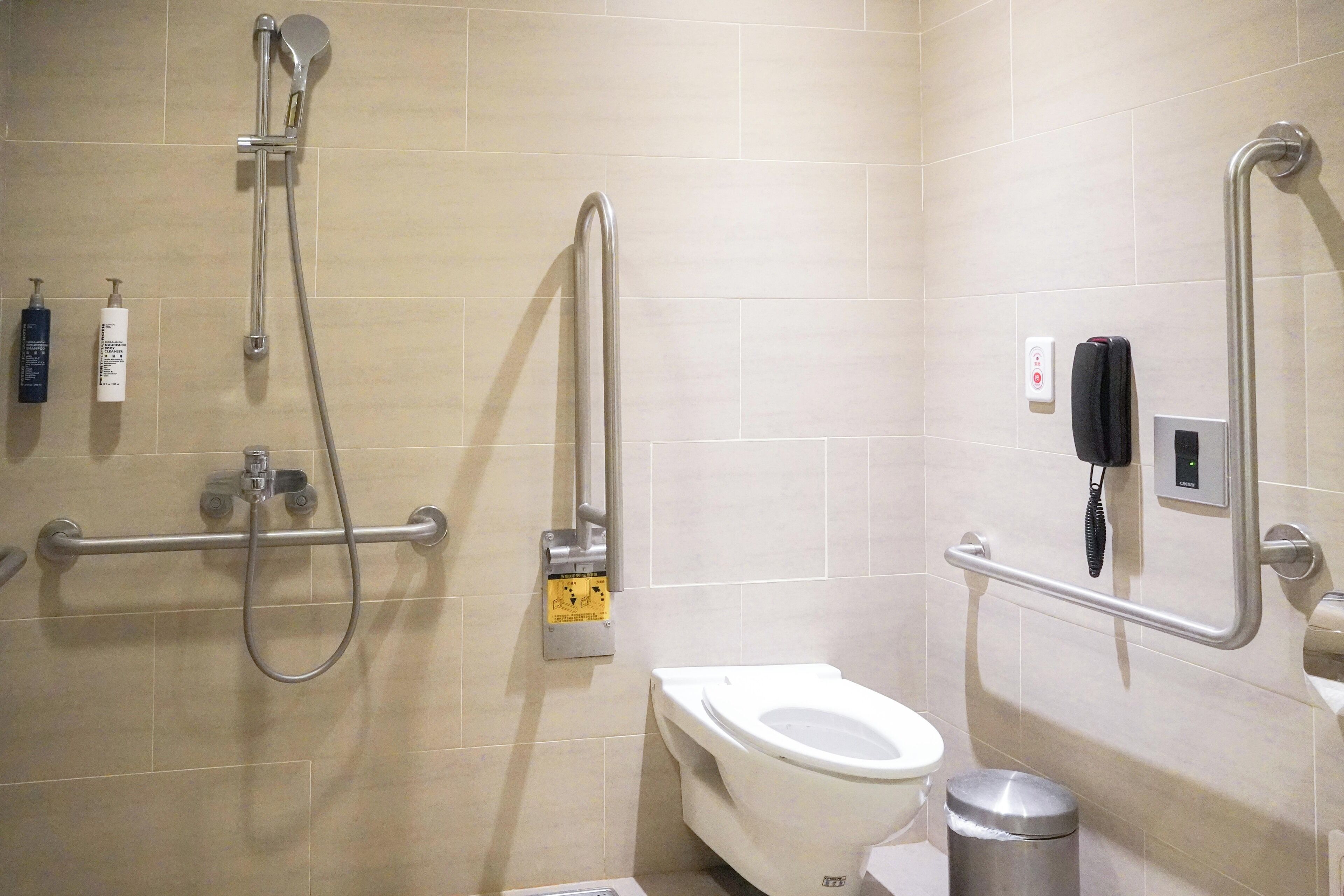 A bathroom with a toilet, a bidet, a hand dryer, and a trash can.