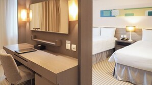 Ein Hotelzimmer mit Schreibtisch, Stuhl, zwei Betten, Nachttischen, Lampen und einem großen Spiegel.