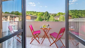 A balcony with a table and chairs, a view of buildings and greenery, and a clear sky. - La Dolce Laveno, Balcony Apartment With A/C (Laveno Mombello)