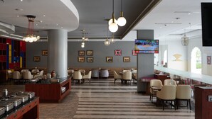 En hotellobby med ett område för buffé, sittplatser och en tv-skärm som visar ett program.