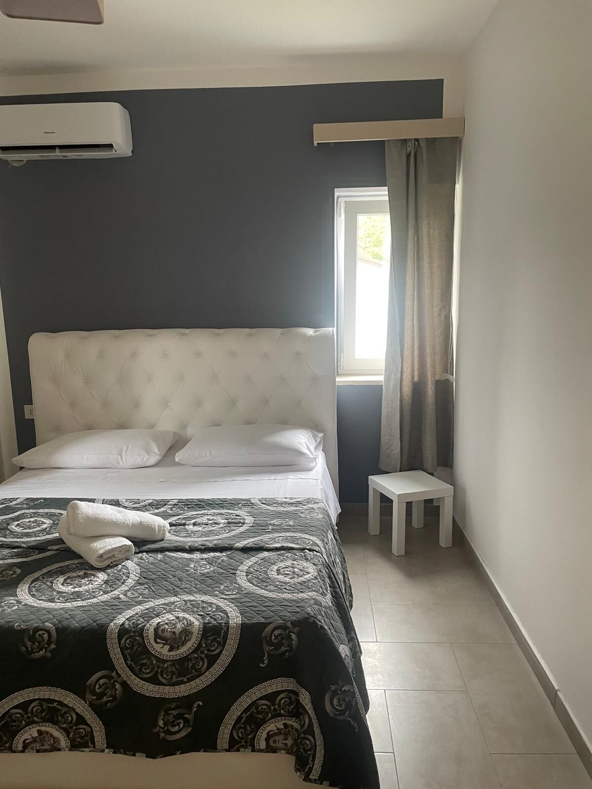 Une chambre avec un grand lit, une table de chevet et une fenêtre avec des rideaux.