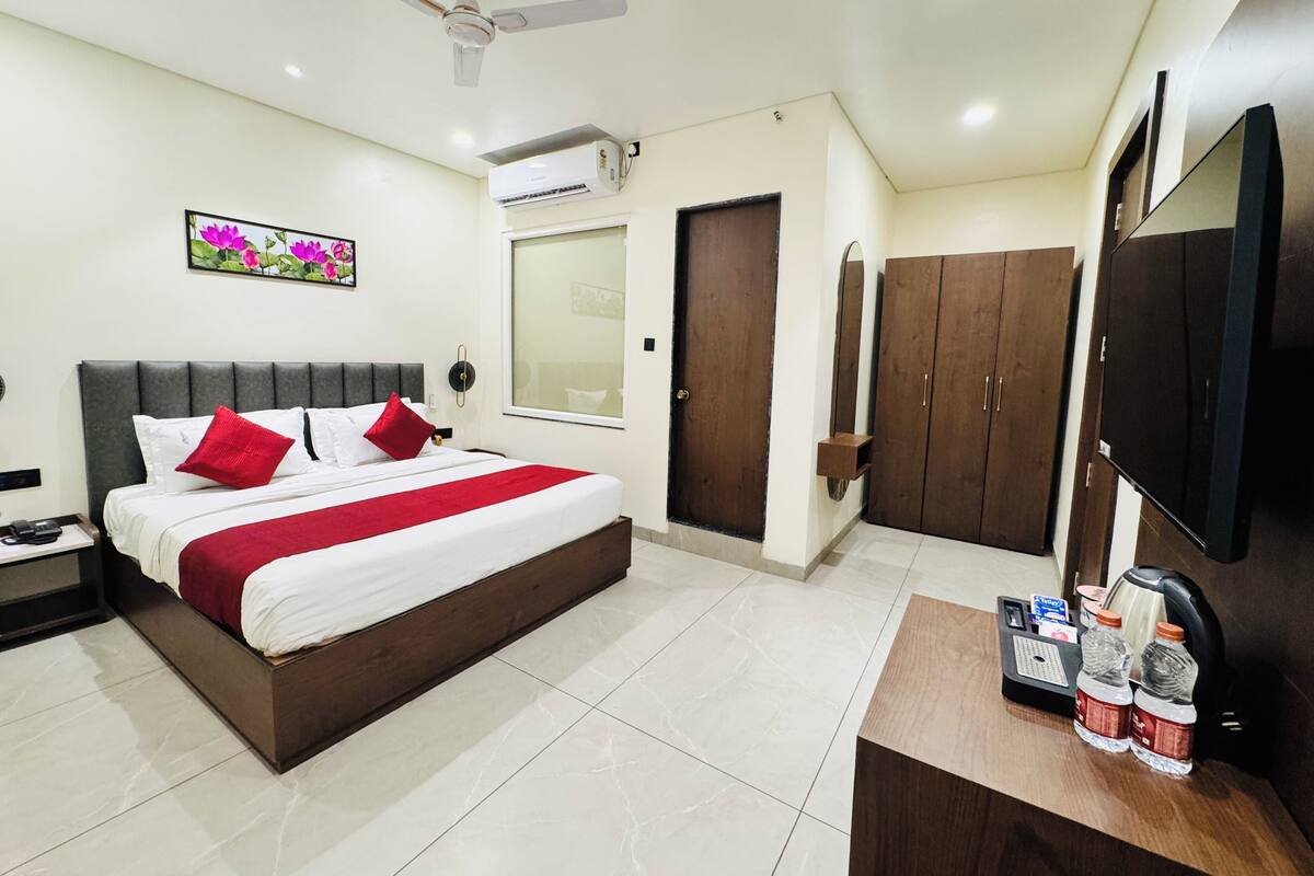 A hotel room with a bed, a desk, a wardrobe, a ceiling fan, and an air conditioning unit.