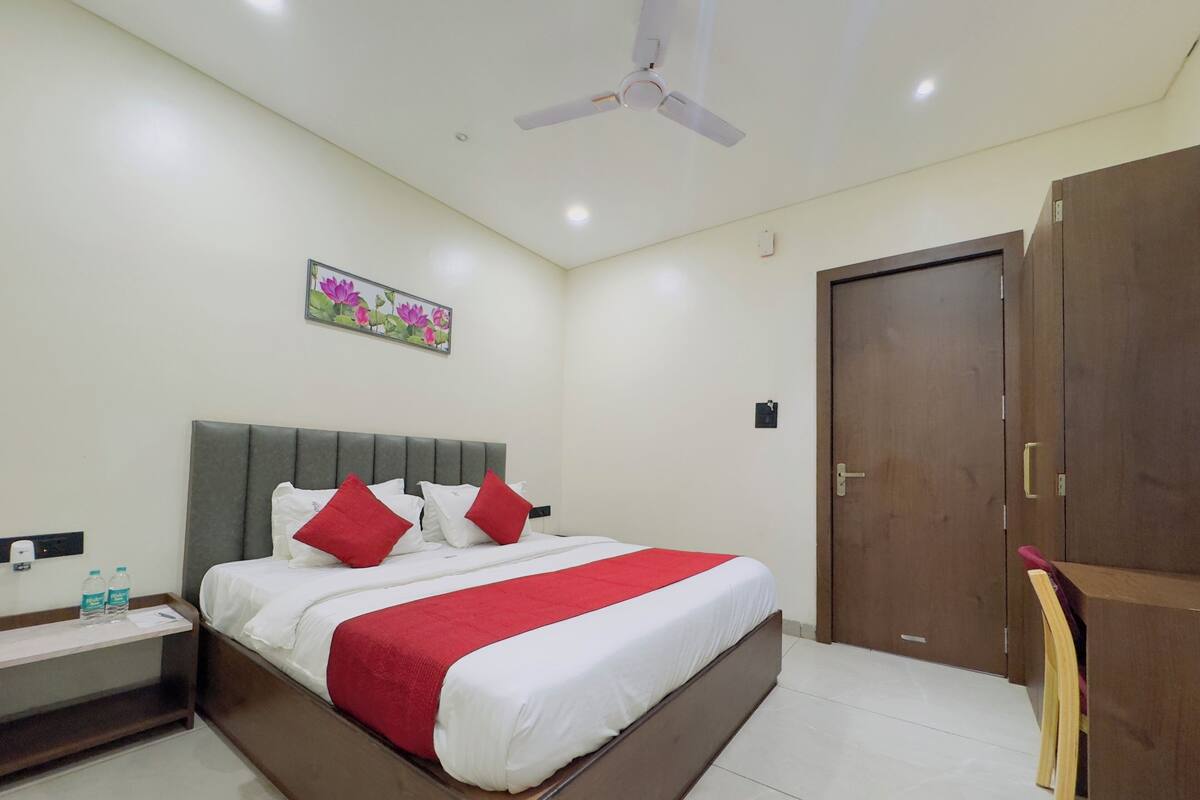A hotel room with a bed, a nightstand, a wooden wardrobe, a ceiling fan, and a wall-mounted picture.