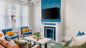 Una sala moderna con chimenea, un televisor de pantalla plana montado encima y asientos cómodos, incluyendo un sofá y sillones.