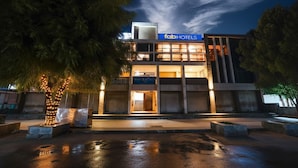 Un edificio moderno con un letrero de 'fab hotels', con fachada de vidrio y una entrada bien iluminada.