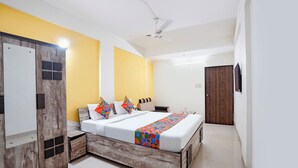 Una habitación de hotel con cama, mesita de noche, armario, ventilador de techo y puerta.