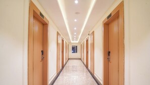Un long couloir bien éclairé, avec des portes en bois, chacune portant un numéro.