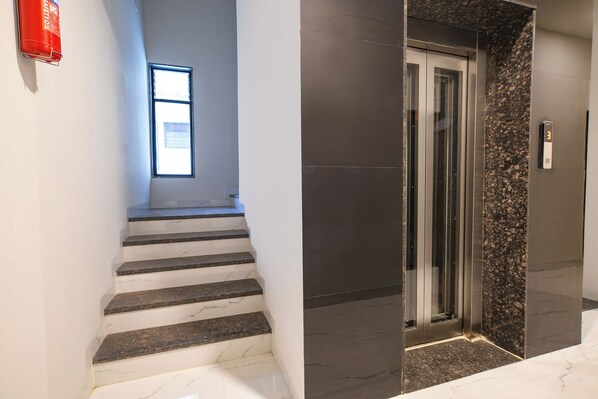 A staircase with marble steps and a fire extinguisher on the wall.