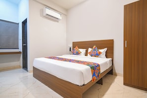 A hotel room with a bed, a wardrobe, a wall-mounted air conditioner, and a telephone. - Fabhotel Evanka (Indore)