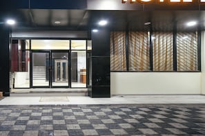 A hotel entrance with a glass door, a staircase leading inside, and a patterned wall. - Fabhotel Evanka (Indore)