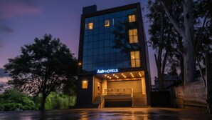 A modern hotel building with a glass facade, a visible entrance, and a sign reading "fabHOTELS". - Fabhotel Evergreen (Faridabad)