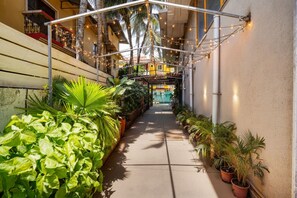 A narrow alleyway with potted plants on both sides, a covered walkway overhead, and a building entrance in the background. - Fabhotel Bagatel (Calangute)