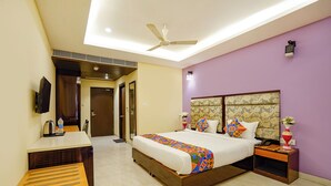 Quarto de hotel com cama, mesa de cabeceira e escrivaninha com cadeira.