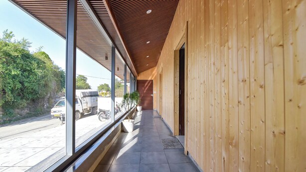 A corridor with wooden walls and large windows overlooking a street. - Fabhotel Green Acres (Dehradun)