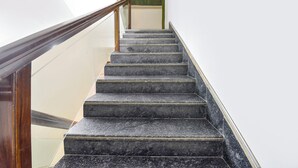 A staircase with dark marble steps and wooden handrails. - Fabhotel Green Acres (Dehradun)