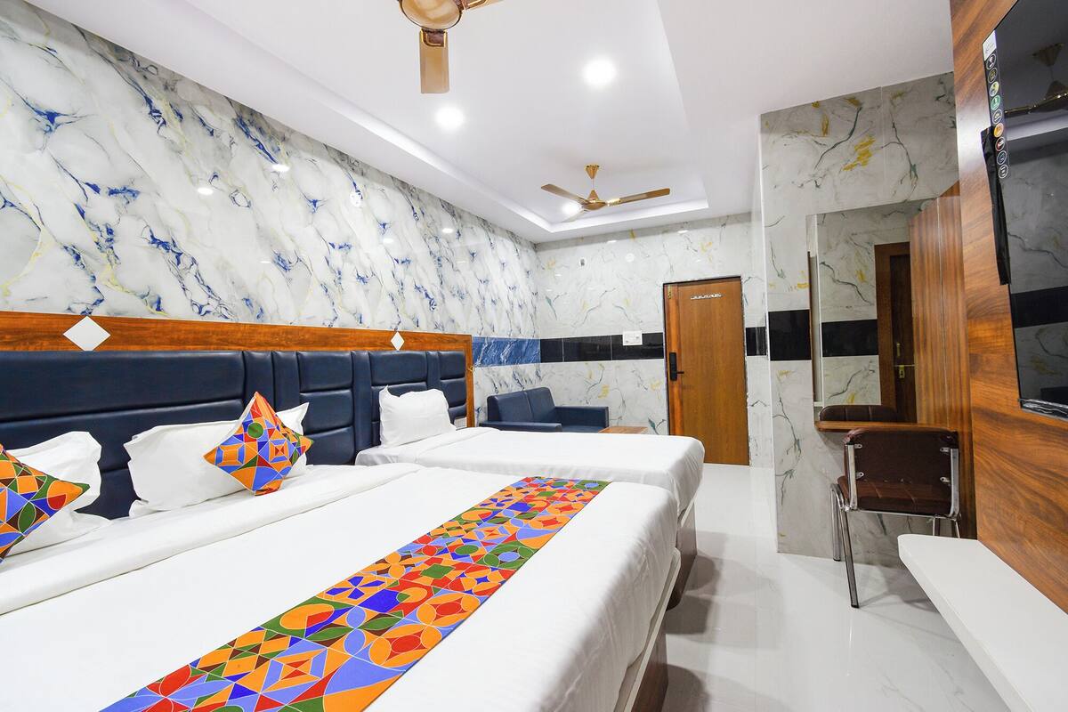 A hotel room with a large bed, a wooden headboard, a blue sofa, a desk, and a mirror.