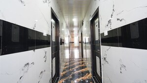 A hallway with glossy marble walls and floors, featuring a central reflective black and gold pattern. - Fabhotel Sunrise (Hyderabad)