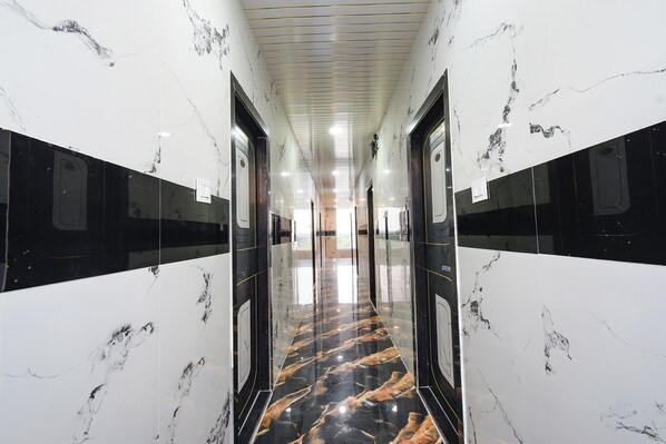 A hallway with glossy marble walls and floors, featuring a central reflective black and gold pattern. - Fabhotel Sunrise (Hyderabad)