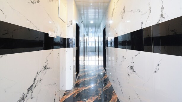 A corridor with marble walls and floors, featuring a modern design with recessed lighting and a glass ceiling. - Fabhotel Sunrise (Hyderabad)
