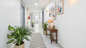 A hallway with a potted plant, a striped rug, and a wooden table with a lamp. - FabHotel Prime Unnam (Hyderabad)