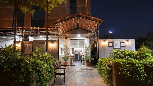 An outdoor entrance with a covered seating area, potted plants, and a pathway leading to the building. - FabHotel Prime Unnam (Hyderabad)