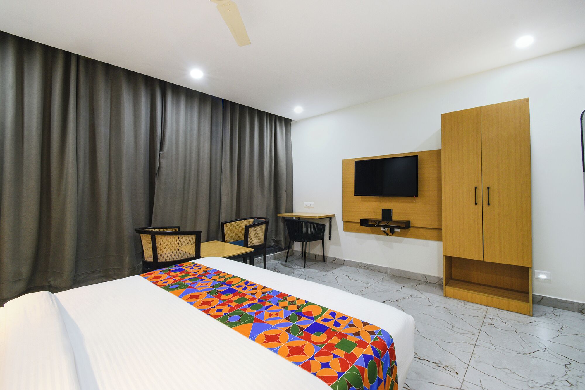 Una camera d'albergo con un letto, una scrivania, due poltrone, una TV a parete e un armadio.