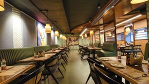 A restaurant with booths and tables, featuring patterned wallpaper and hanging lamps. - FabHotel Prime Unnam (Hyderabad)