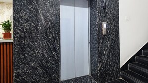 A modern elevator with a marble wall, a potted plant, and a staircase. - FabHotel Prime Unnam (Hyderabad)