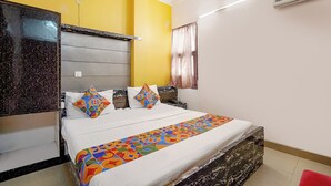 Un dormitorio con cama, cabecera, ventana con cortinas y equipo de aire acondicionado.