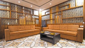 A living room with two brown sofas, a coffee table, patterned wallpaper, and a tiled floor.