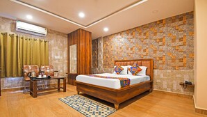 A hotel room with a wooden bed, a desk with chairs, a patterned rug, and a decorative wall.