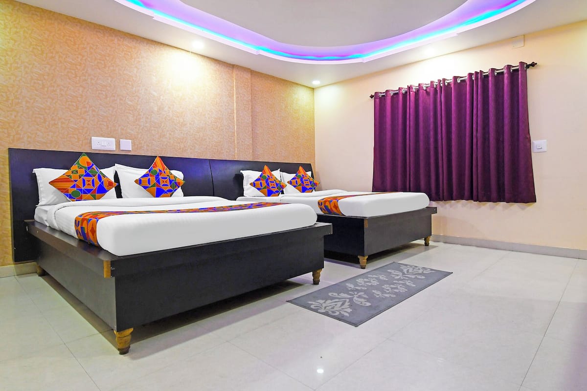 A hotel room with two beds, a purple curtain, and a patterned rug.