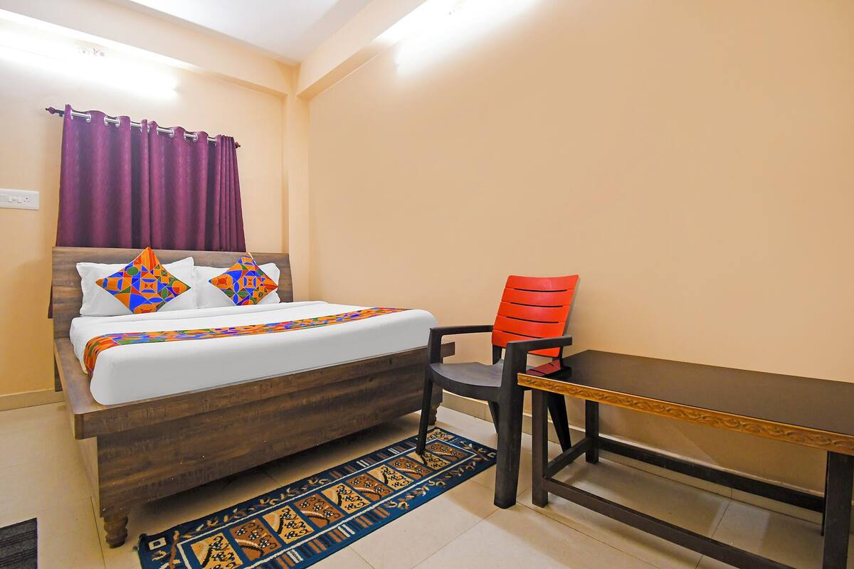 A bedroom with a bed, a table, and a chair.