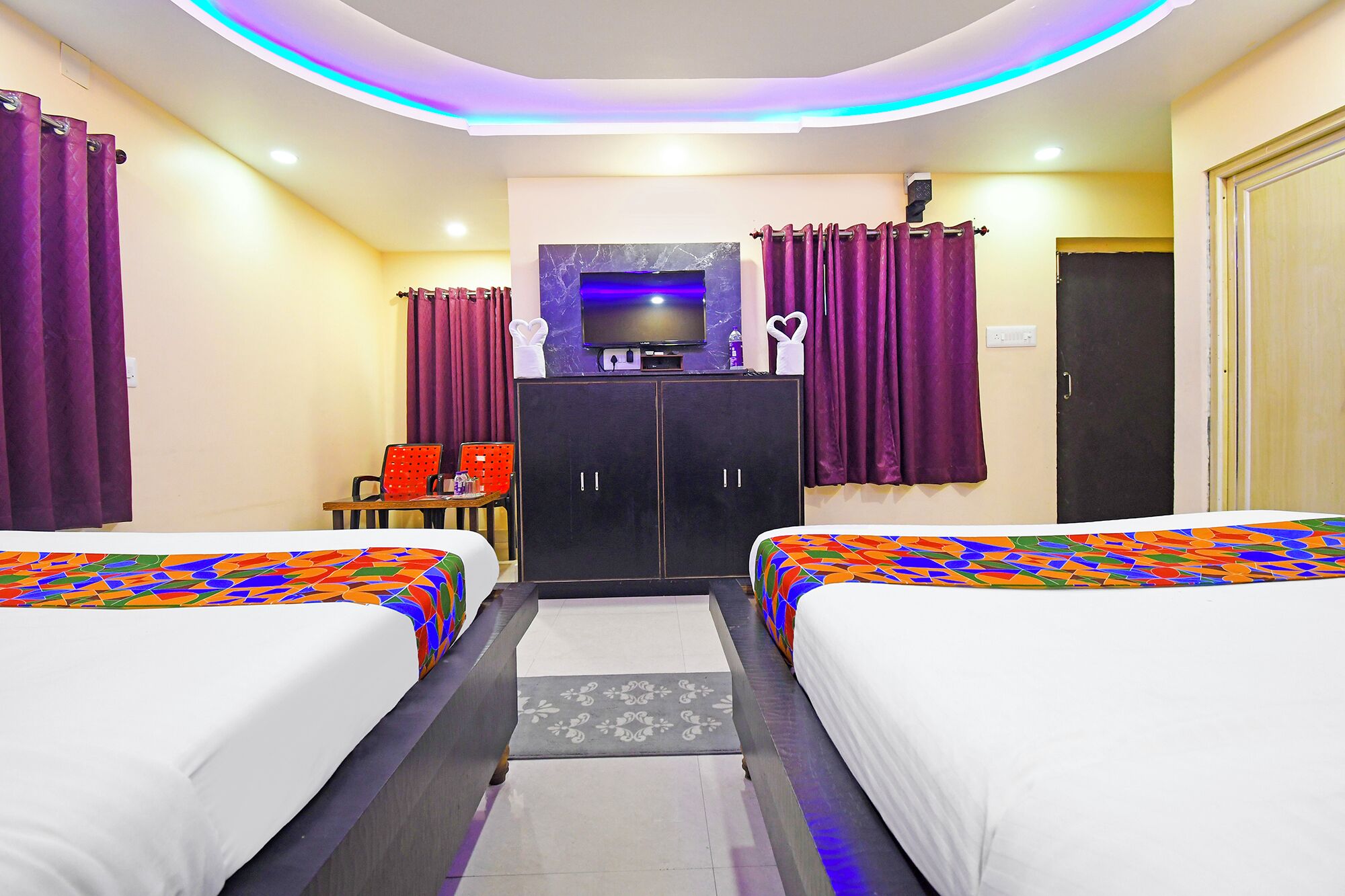 A hotel room with two beds, a TV, a desk, and a wardrobe.