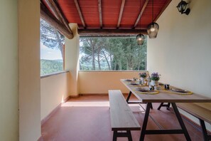 Un'area pranzo con un tavolo di legno apparecchiato per due persone, una panca e vista sull'esterno.