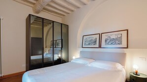 A bedroom with a large bed, a wardrobe, and two framed pictures on the wall. - Casa Riccimballa (Impruneta)