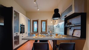 A modern kitchen with a central island, built-in appliances, and a pendant light. - Casa Riccimballa (Impruneta)